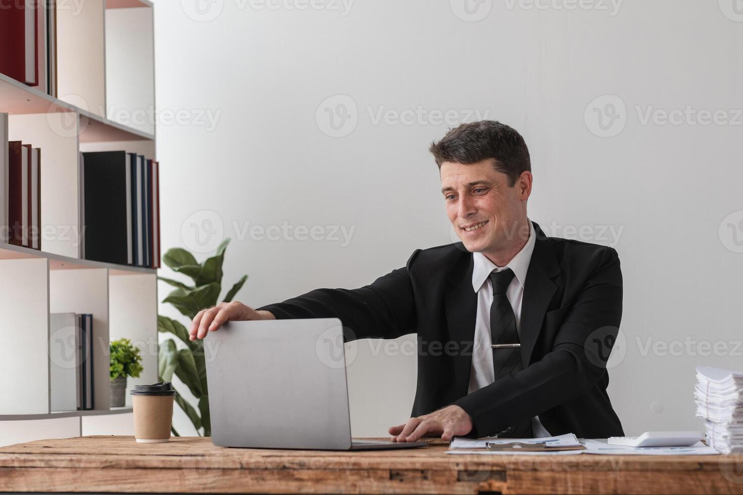 Businessman Working in Modern Office with Laptop and Documents, Professional Corporate Environment, Office Workspace, Business Attire, Productivity, and Focused Work photo