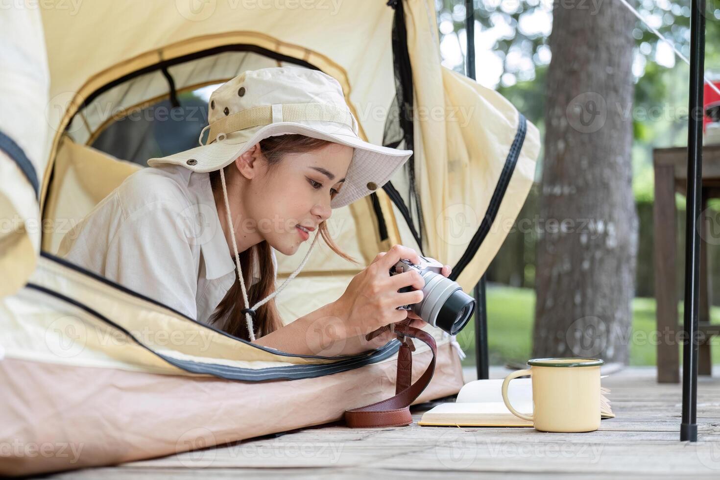 Young Woman Enjoying a Camping Adventure in the Forest with Camera and Journal Inside a Tent photo