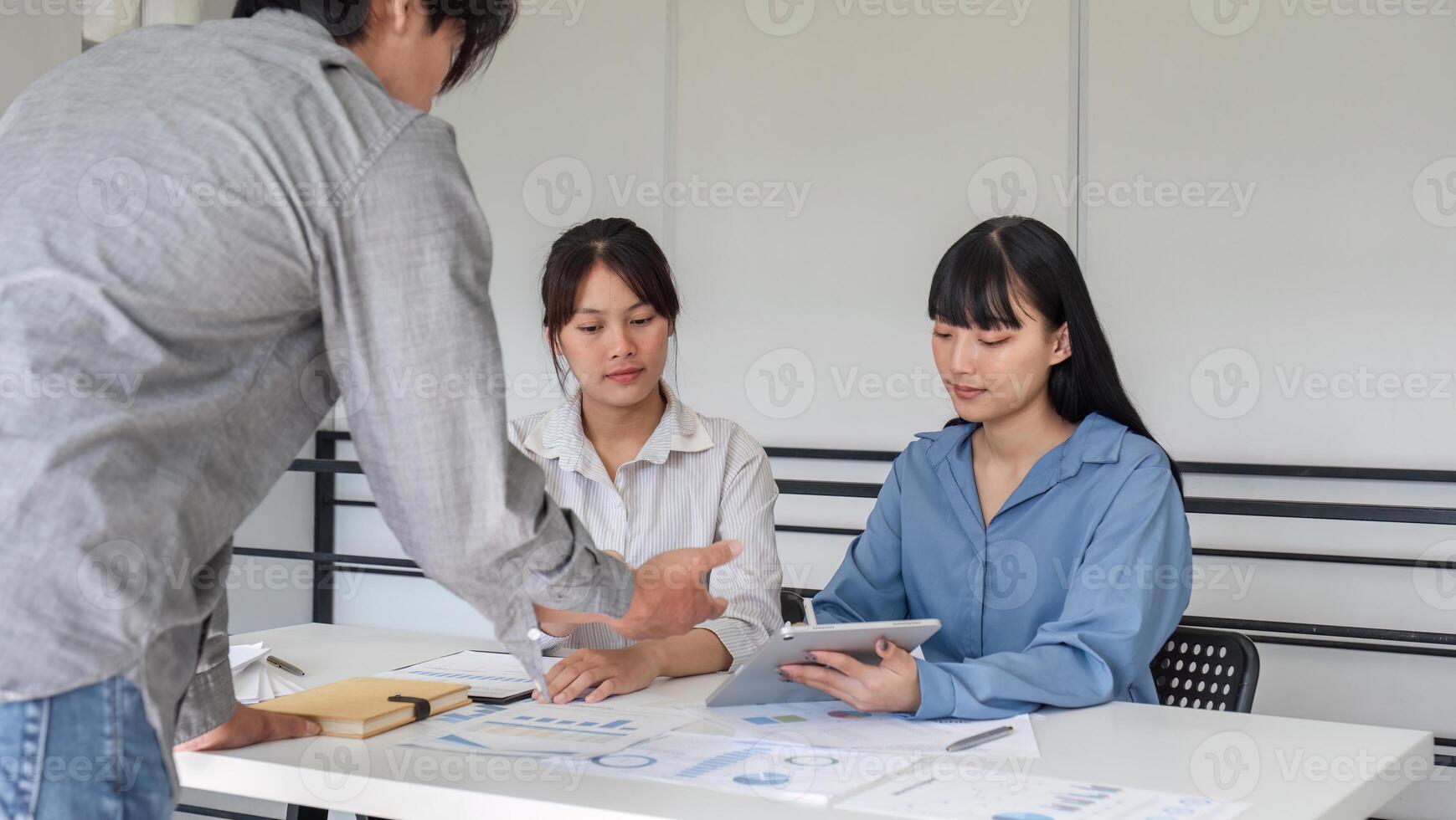 Young Business Team Collaborating on Marketing Strategy with Digital Tablet and Documents in Modern Office photo