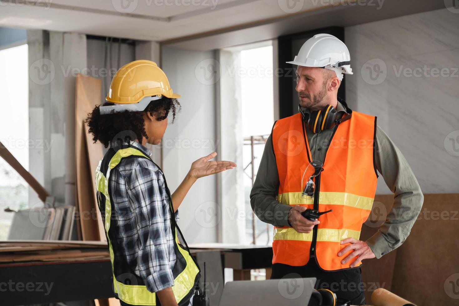 Engineering Team Discusses Construction Plans on Site with Safety Gear and Blueprints in Modern Building Interior photo
