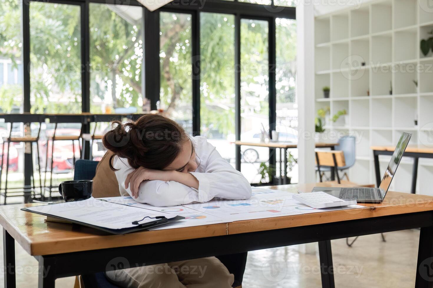 Exhausted Office Worker Sleeping at Desk with Laptop and Documents in Modern Workspace photo
