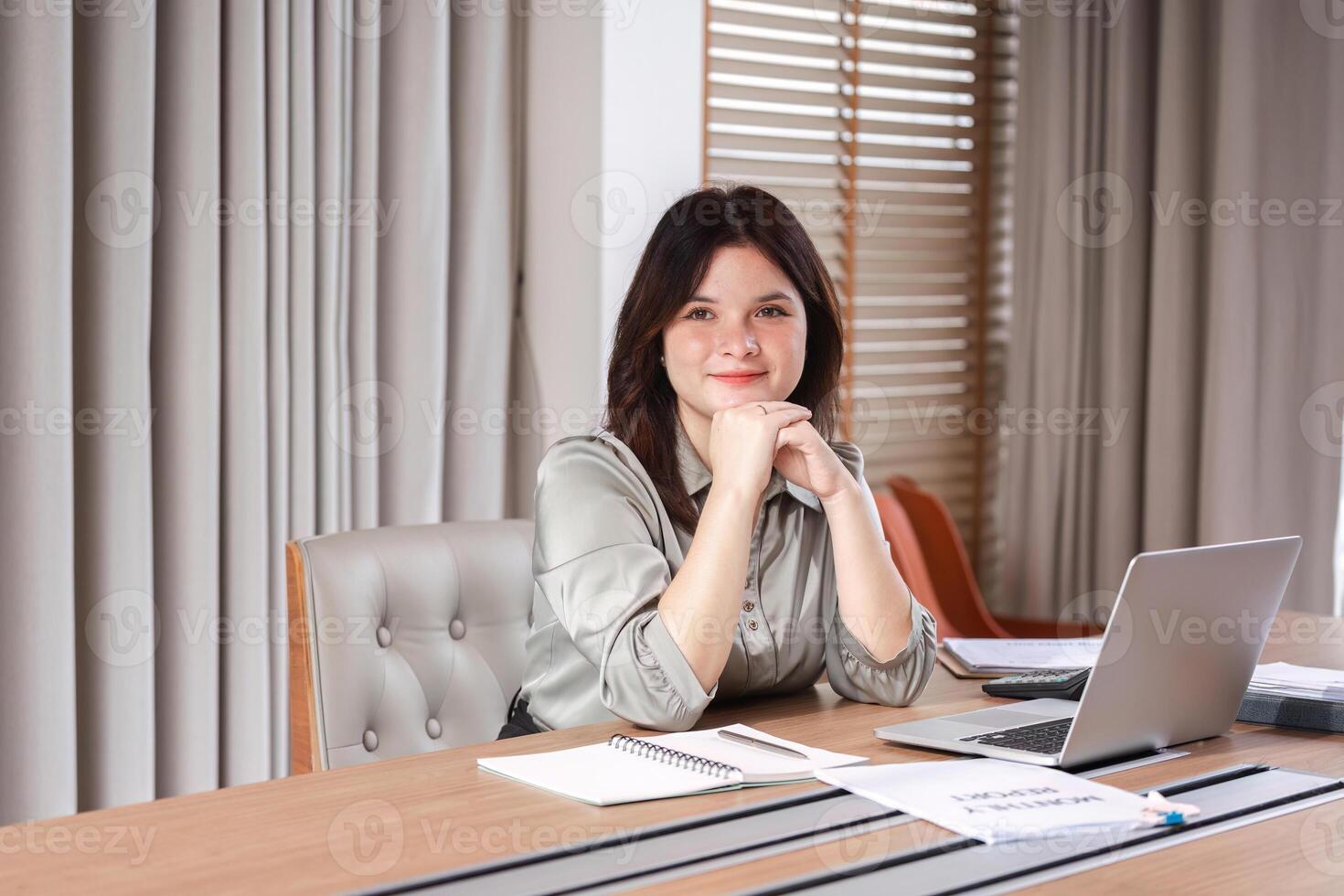 Businesswoman Strategizing and Organizing Work with Documents and Laptop in Modern Office Setting photo