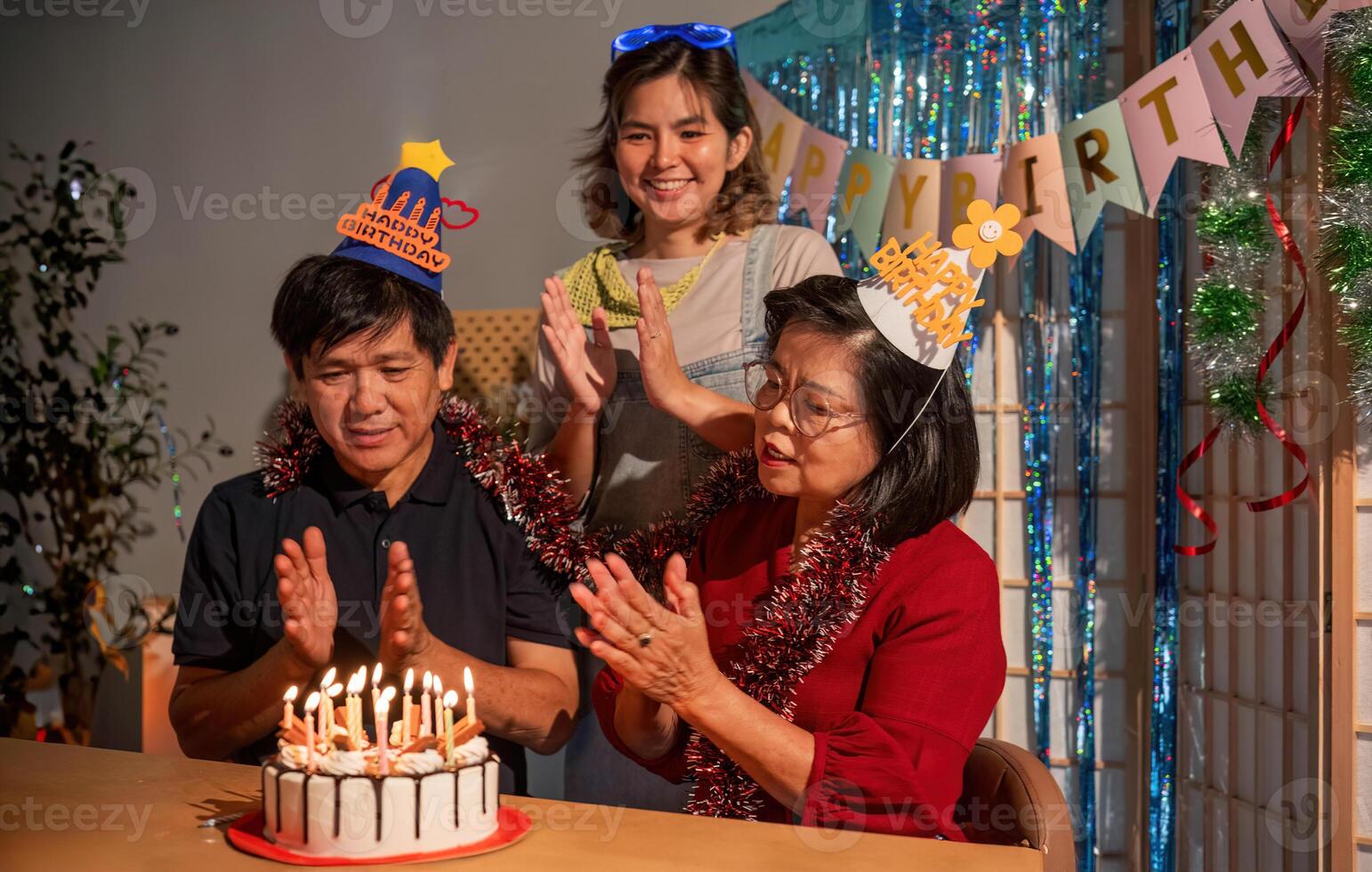 A man and woman are celebrating a birthday with a cake and hats photo
