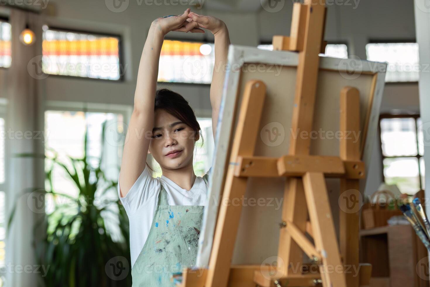Talented Female Artist Painting on Canvas in Bright Studio with Natural Light and Greenery in the Background photo