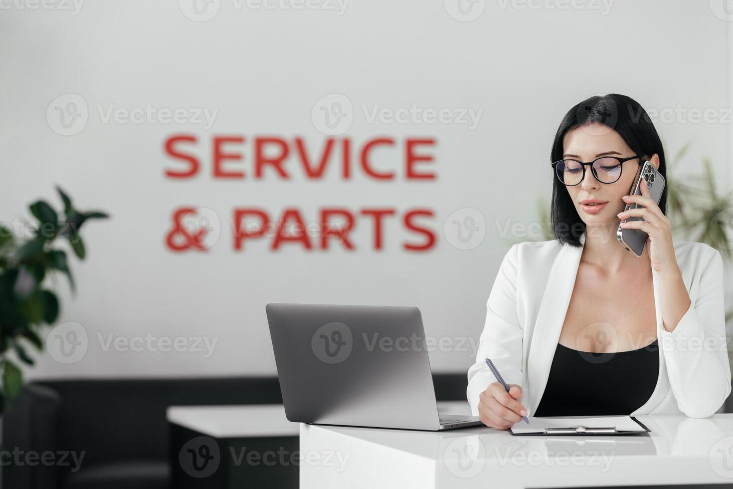 Professional sales manager talking, consulting about auto to female client in dealership by smartphone and helps to choose electric car. Buying, renting and insuring a car. photo