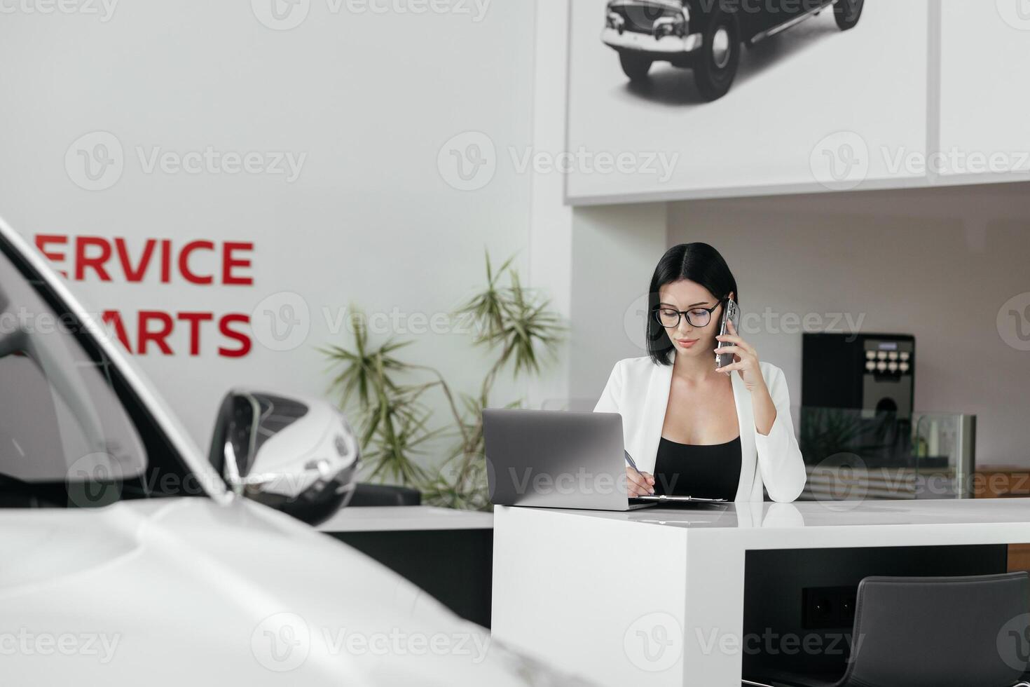 Professional sales manager talking, consulting about auto to female client in dealership by smartphone and helps to choose electric car. Buying, renting and insuring a car. photo