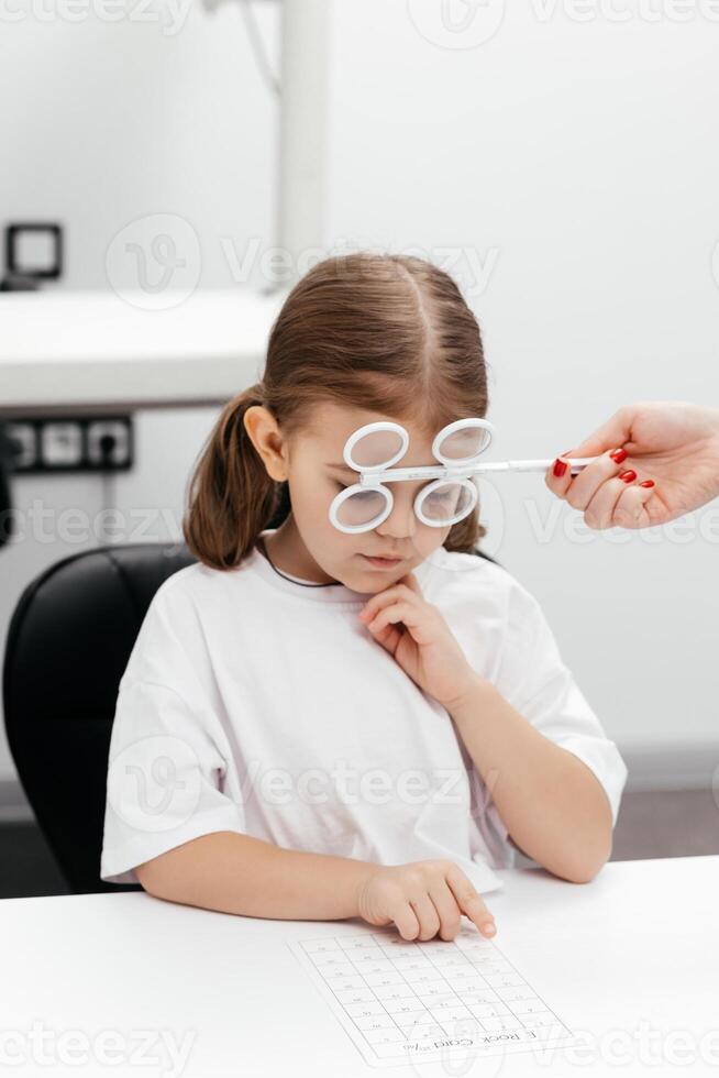 A young girl is practicing her vision skills in a state-of-the-art ophthalmology clinic. Engaging tools and a friendly atmosphere make the experience both fun and beneficial for her development photo