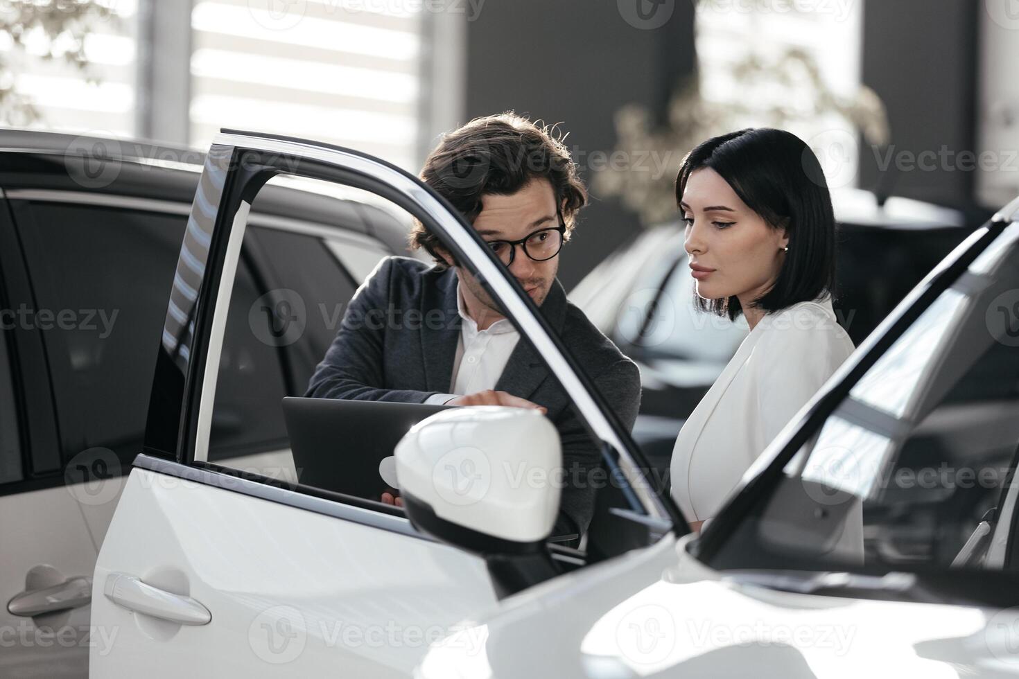 Salesperson working at car dealership. Young man consultant woman buyer, signing contract for new car in auto show. Concept for car rental or sale .Payment bt credit card photo