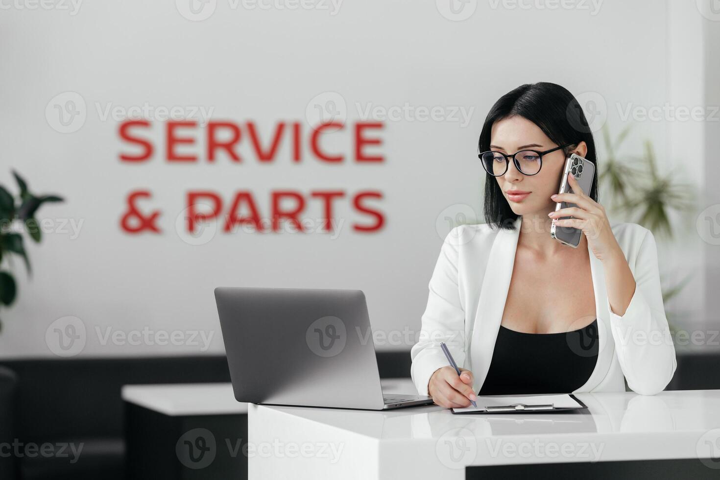 Professional sales manager talking, consulting about auto to female client in dealership by smartphone and helps to choose electric car. Buying, renting and insuring a car. photo