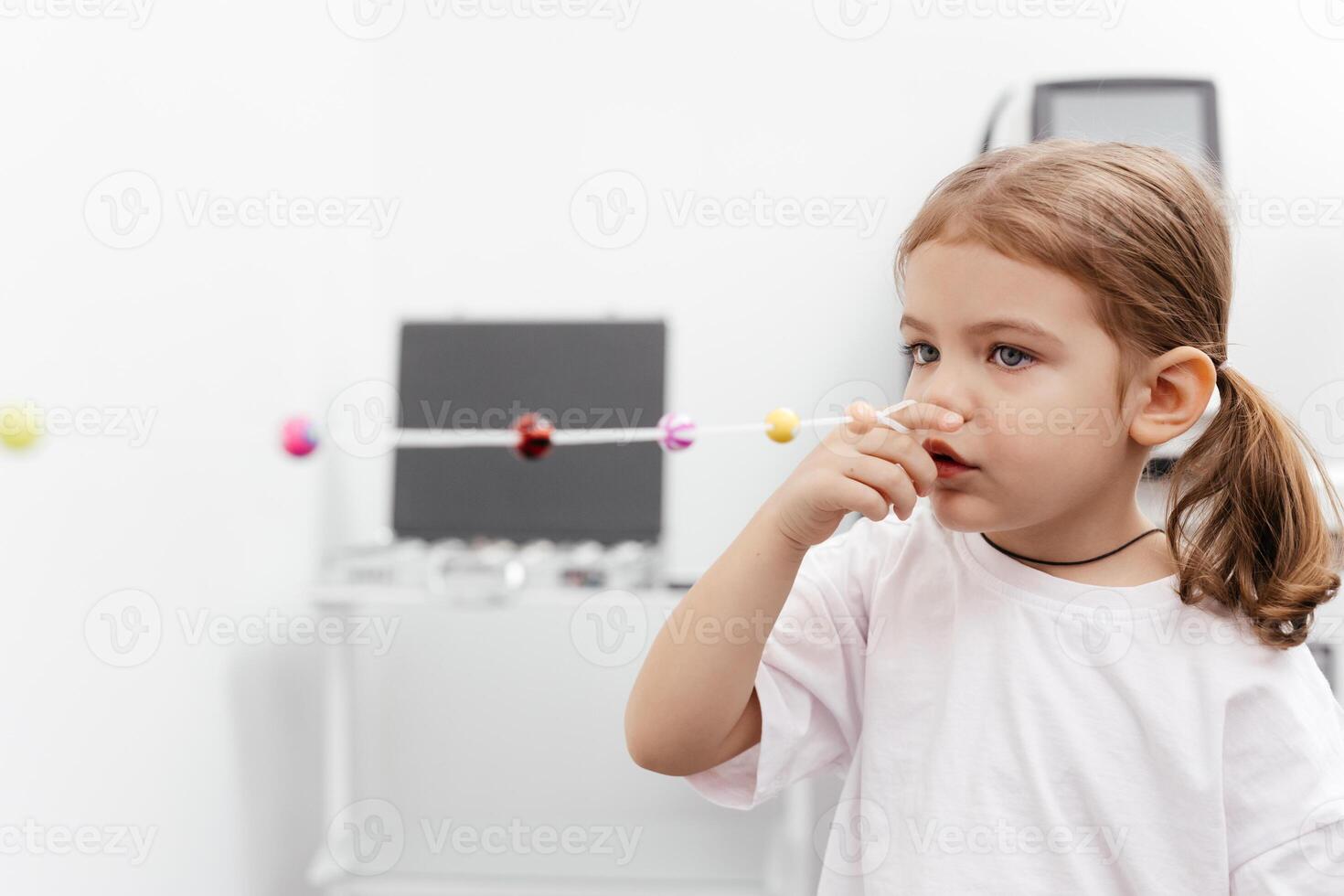 Portrait of a little, happy girl in ophthalmology clinic. Ophthalmic instrument. Excellent moment to illustrate careful examination for children's eye health. Advertisement for pediatric ophthalmology photo