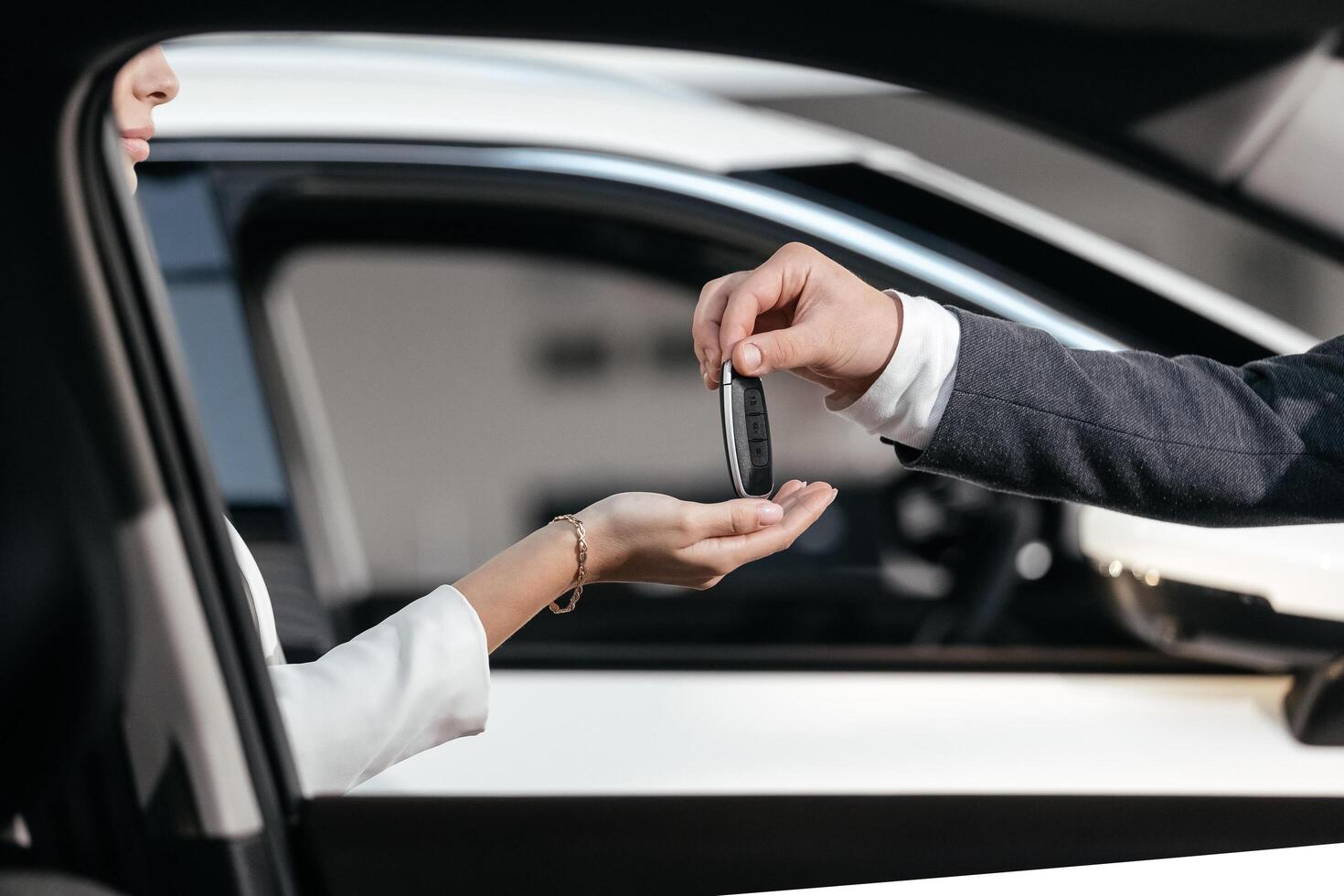 Man in front of the new car and holding keys. Salesman is carrying the car keys delivered to the customer at the showroom. Car key handover concept. Female bought herself a beautiful new car. photo