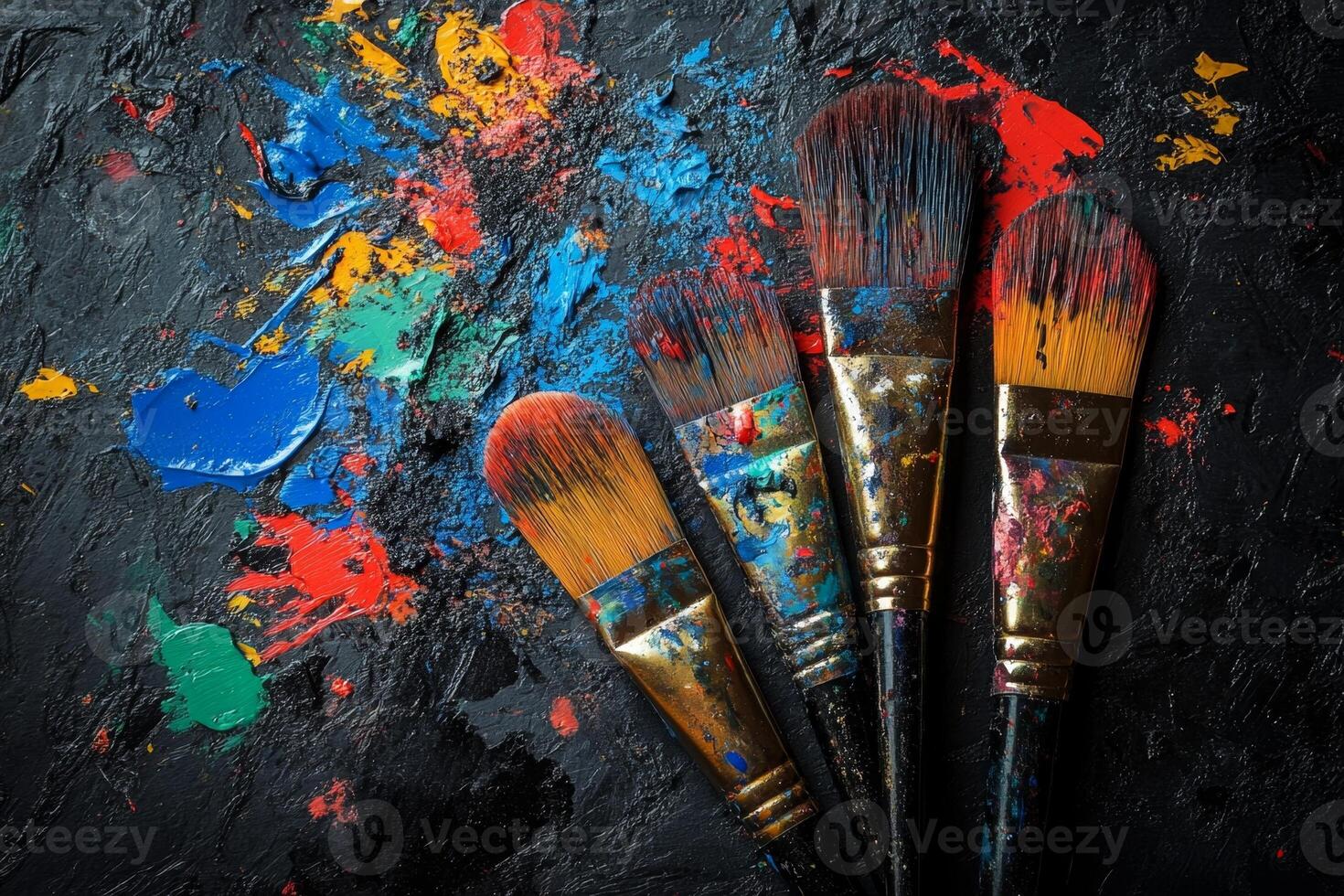 Paintbrushes lying on a black canvas covered in colorful paint photo