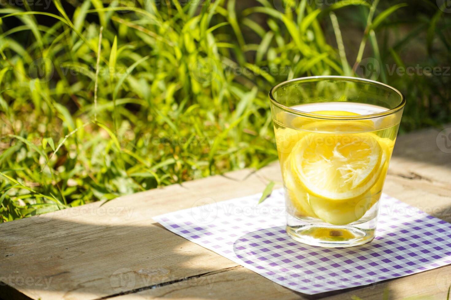 a glass of water lemon with grass background photo