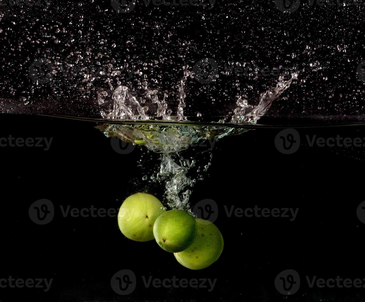 Three green apples are falling into water photo