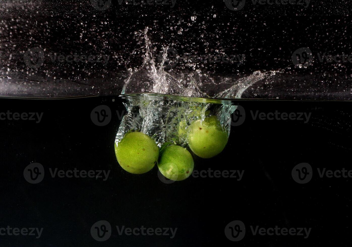 A green fruit falling into water photo