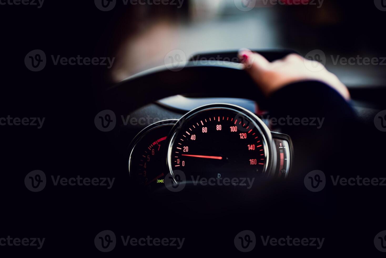 Speedometer instrument cluster visible behind a hand on a steering wheel photo