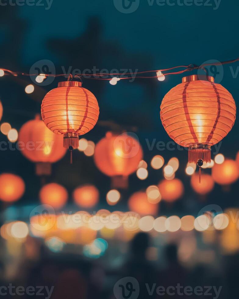 Hanging red lanterns glowing against a night sky, surrounded by bokeh lights and blurred figures celebrating a festival photo