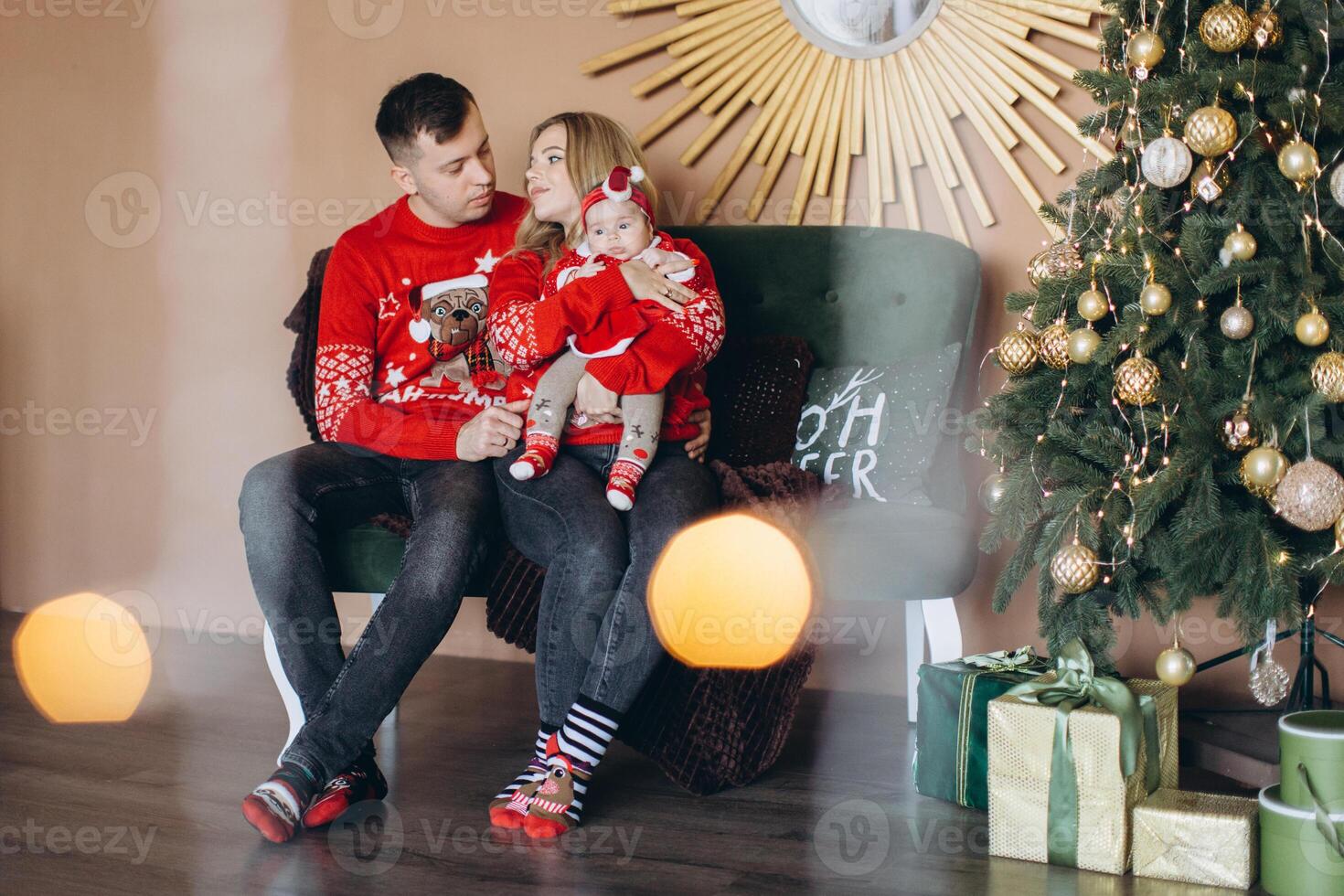 Happy family mom dad and little daughter in red traditional Christmas clothes spending time together near Christmas tree, copy space photo
