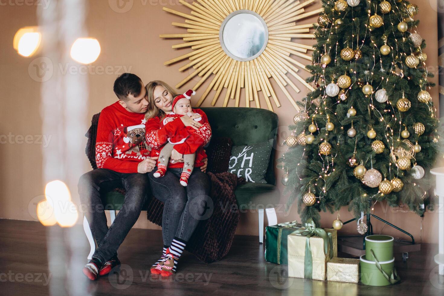 Happy family mom dad and little daughter in red traditional Christmas clothes spending time together near Christmas tree, copy space photo