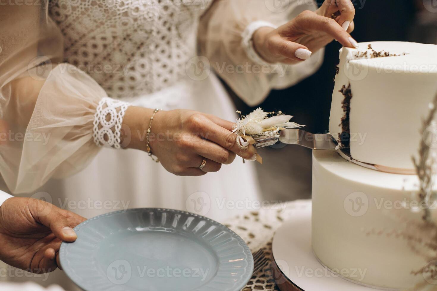 The wedding cake. The bride and groom cut off a piece of cake with a knife. The hands of the newlyweds cut the first piece of the wedding cake. photo