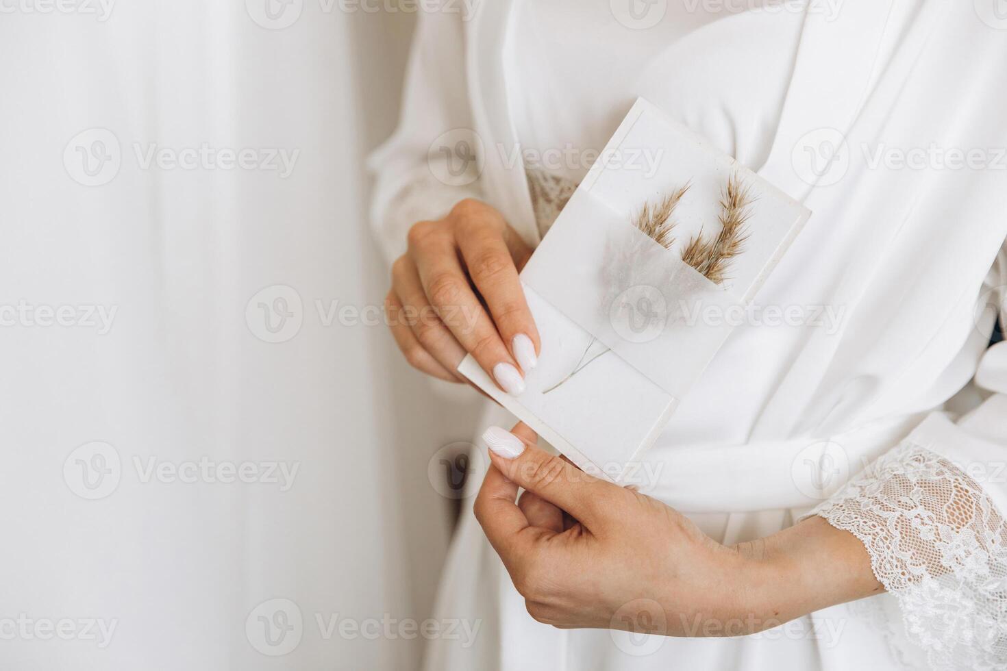 Close-up Bride holds in her hands an envelope with a sheet of paper invitation. Wedding photography, copy space, mock-up. photo