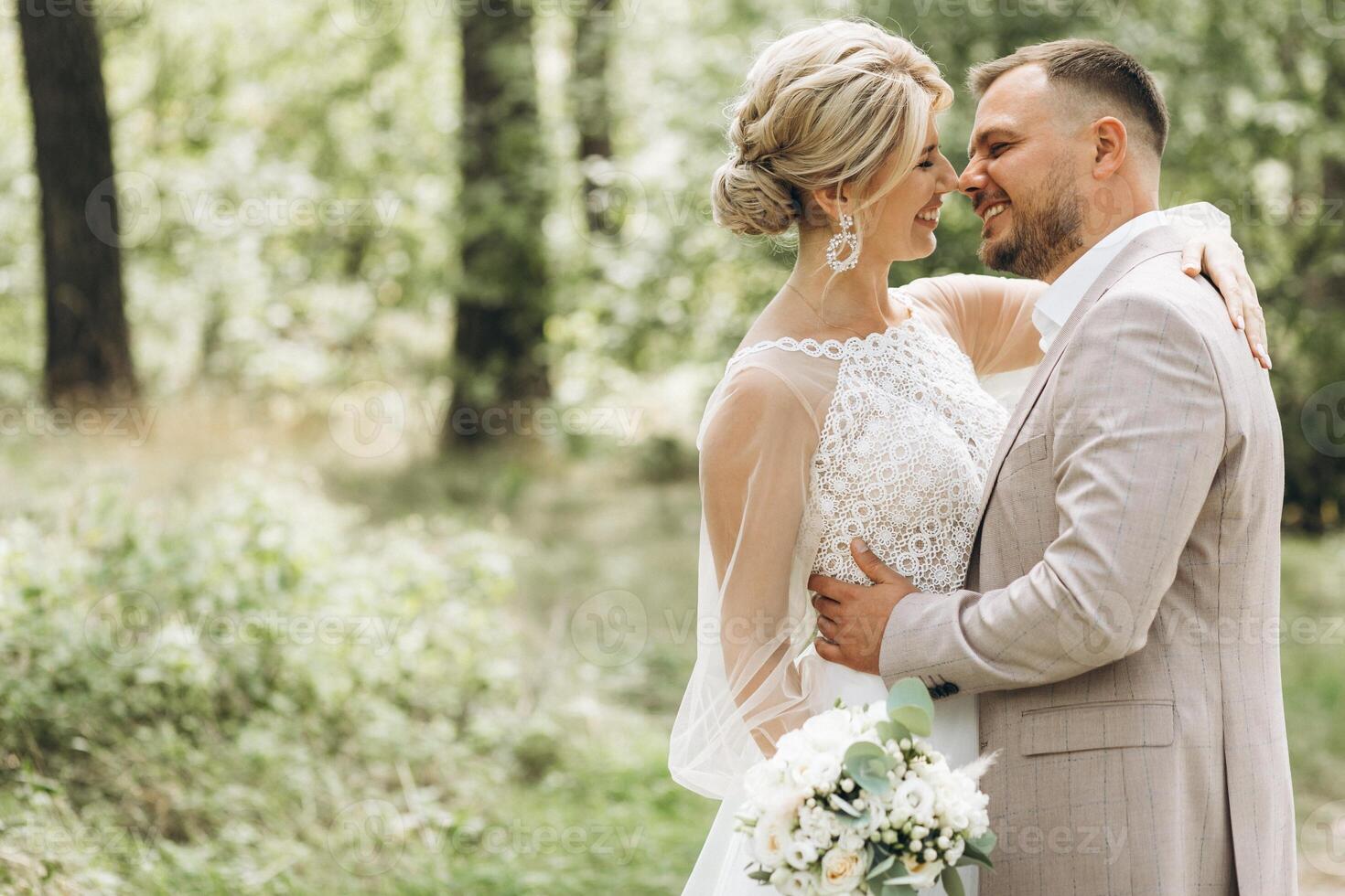 Wedding couple bride and groom walk hand in hand through a pine forest, sunlight filtering through the trees, highlighting their joyful expressions. photo