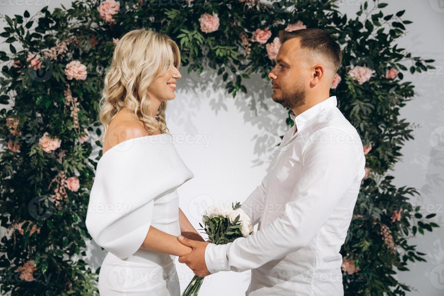 Smiling Couple Embracing Love and Commitment in Romantic Wedding Ceremony with Floral Backdrop photo
