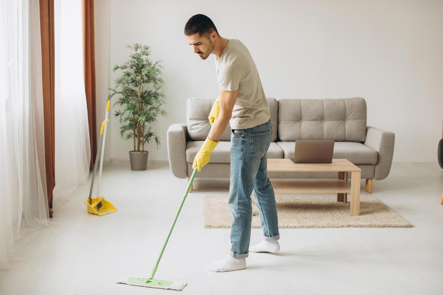 Young man washes the floor with a mop in the room photo