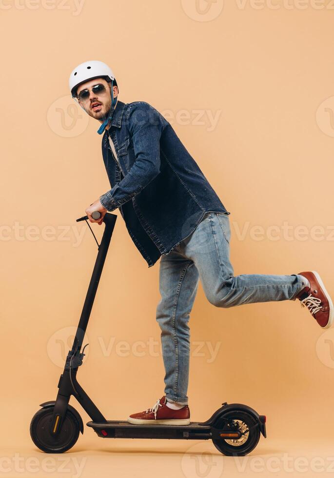 Stylish modern man in a helmet rides an electronic scooter, photo in the studio