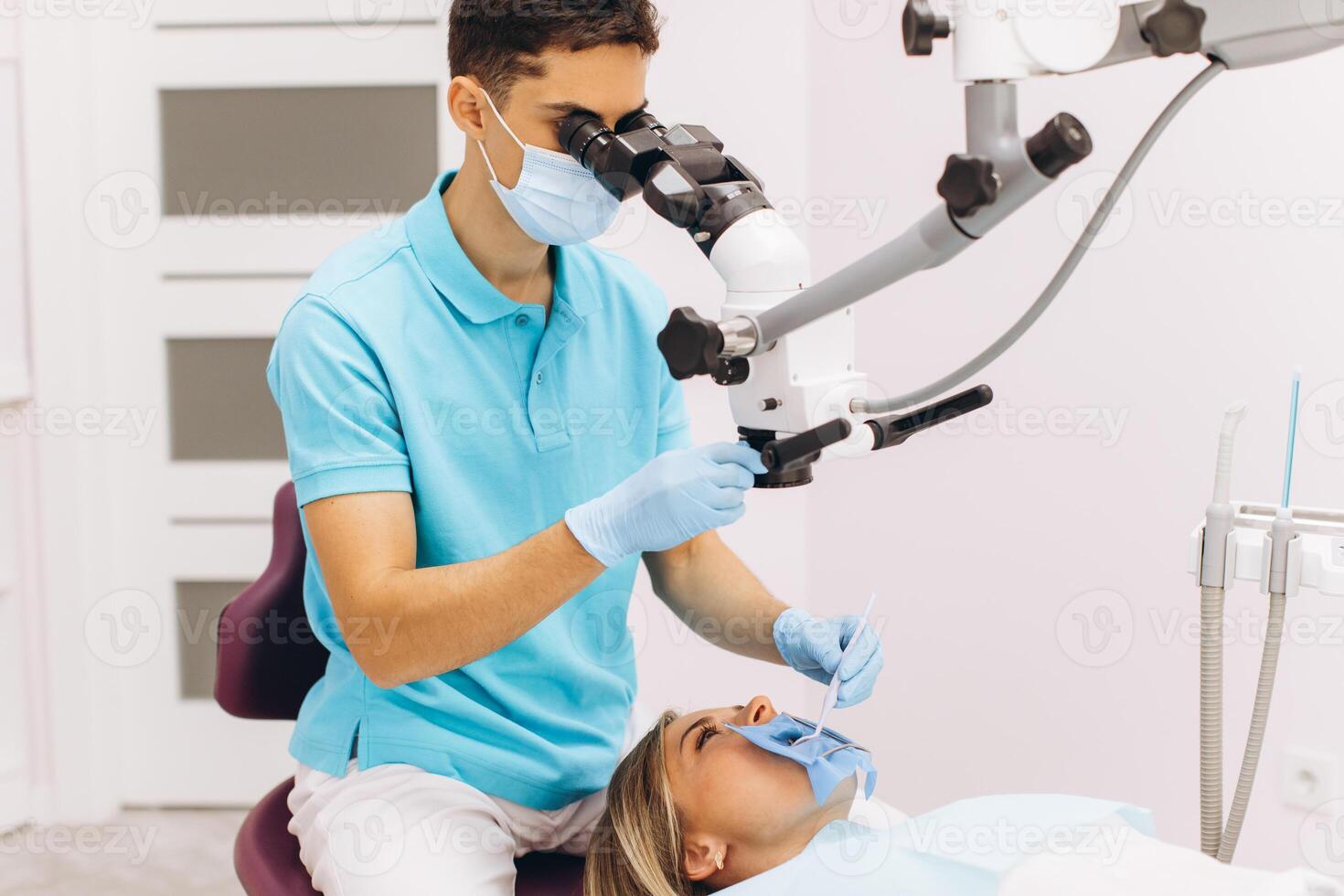 Male dentist examining woman looking on the teeth with professional microscope in the surgery dental office photo