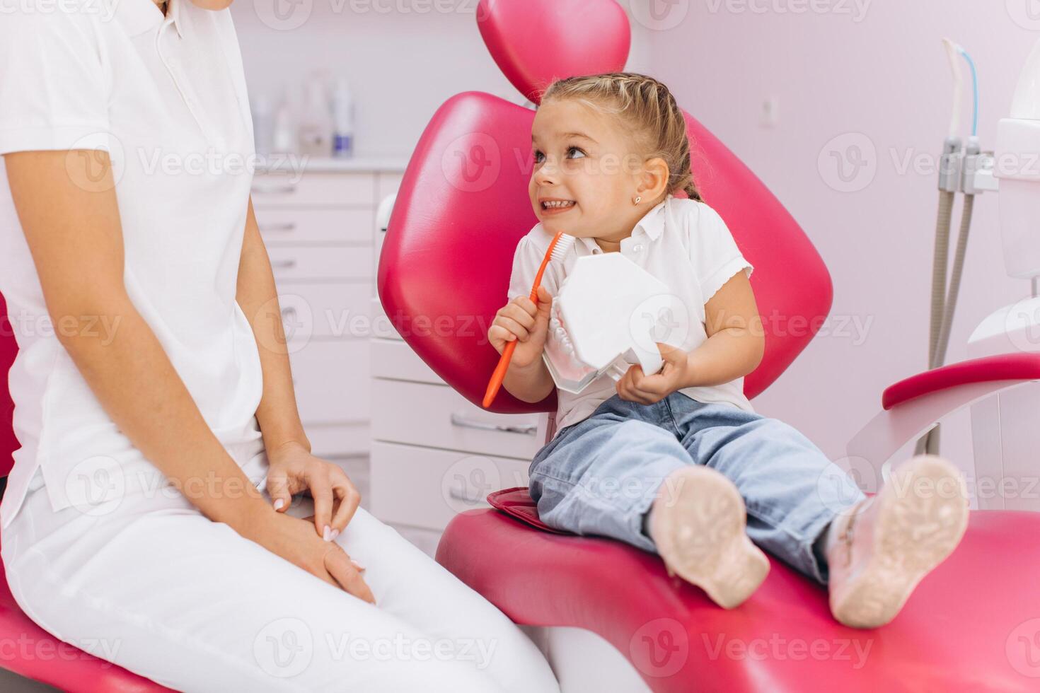 A little girl shows how she brushes the teeth for the woman dentist in a dental clinic photo