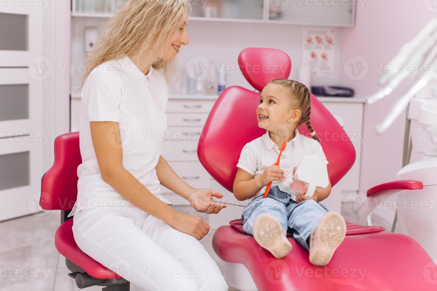 A little girl shows how she brushes the teeth for the woman dentist in a dental clinic photo