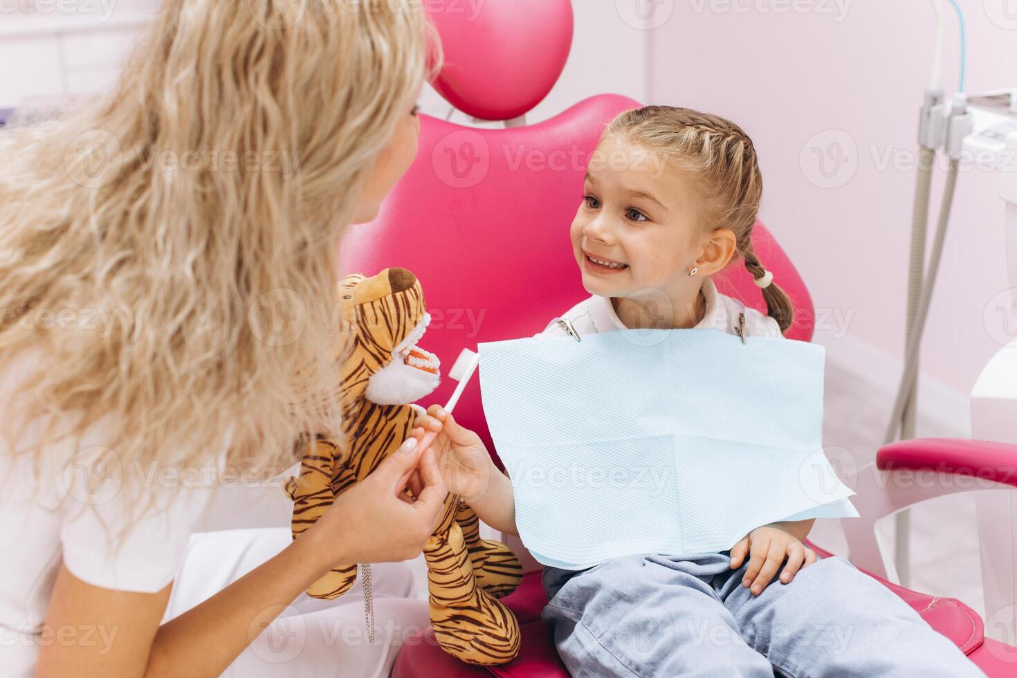 Little girl on a visit to the dentist holding a toy and showing how to brush your teeth in a dental clinic photo