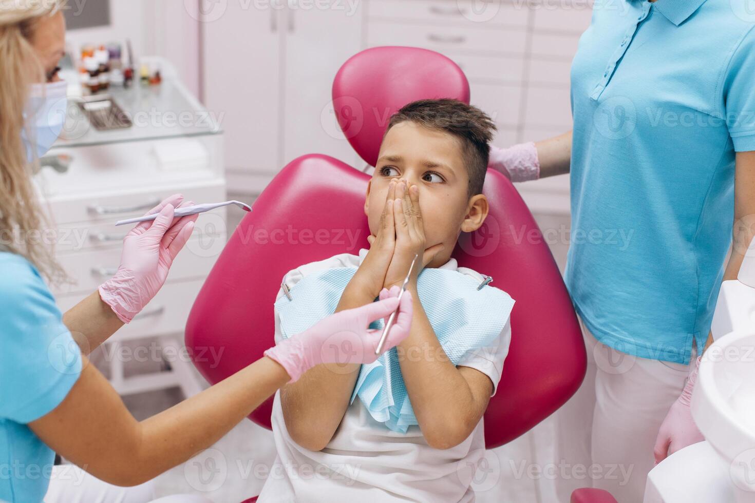 The boy is scared and closes his mouth with his hands on a visit to the dentist at the dental clinic photo