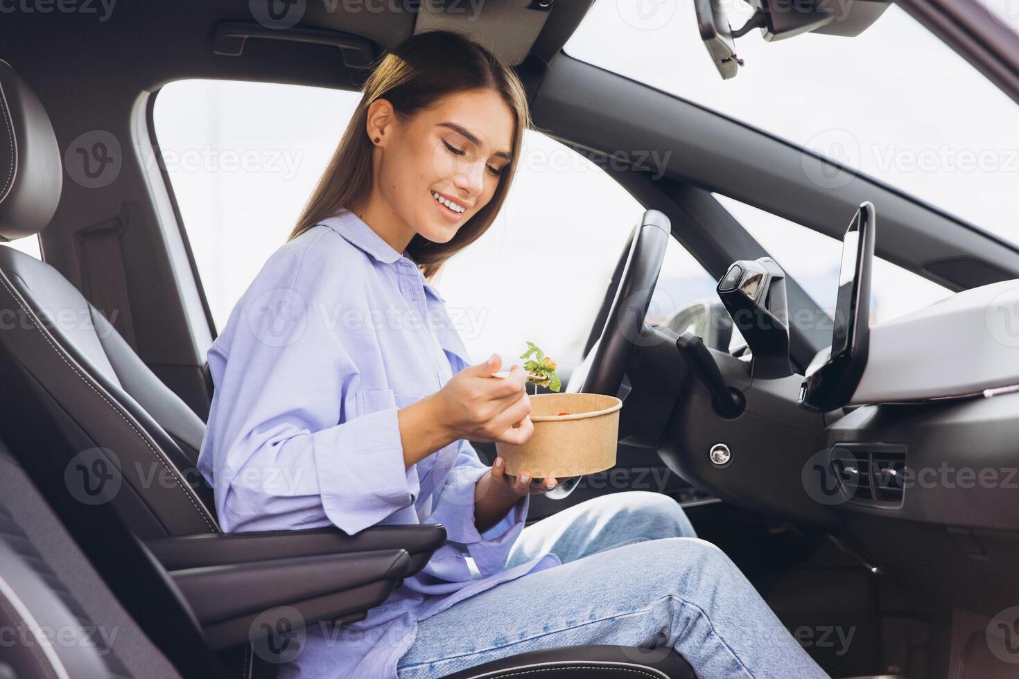 Young Woman Enjoying Healthy Lunch Inside Her Car, Embracing Convenient On the Go Lifestyle with Nutritious Snack during Busy Day photo