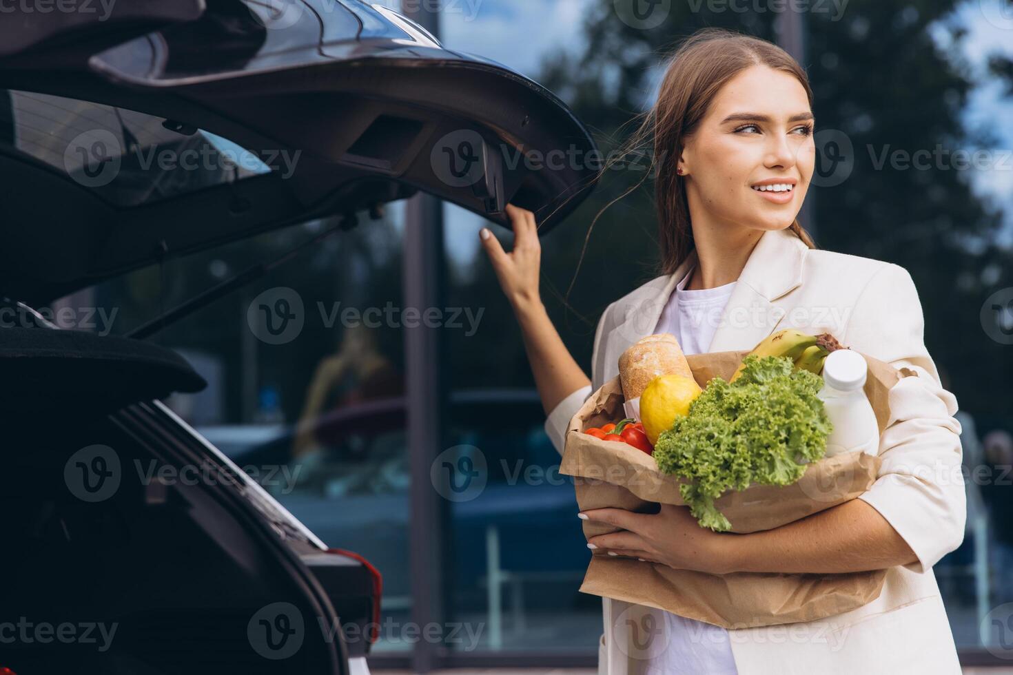 Young Woman Carries Groceries to Car With a Smile photo