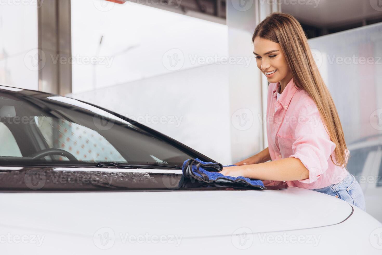 Young Woman Smiling While Cleaning Car at Car Wash photo