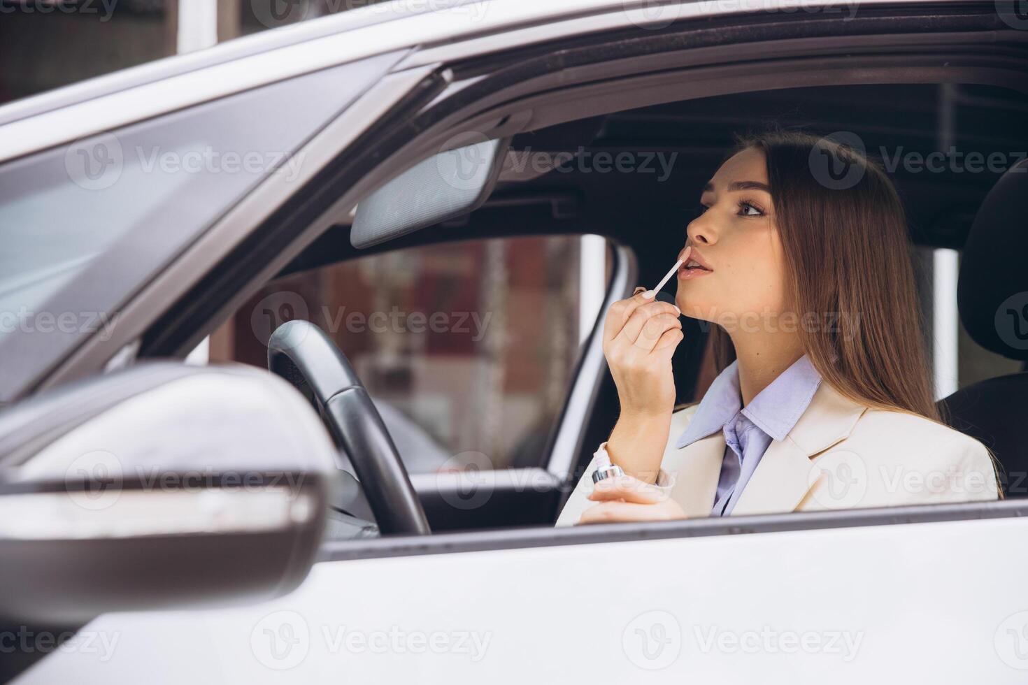 Woman Applying Lipstick While Sitting in a Car photo