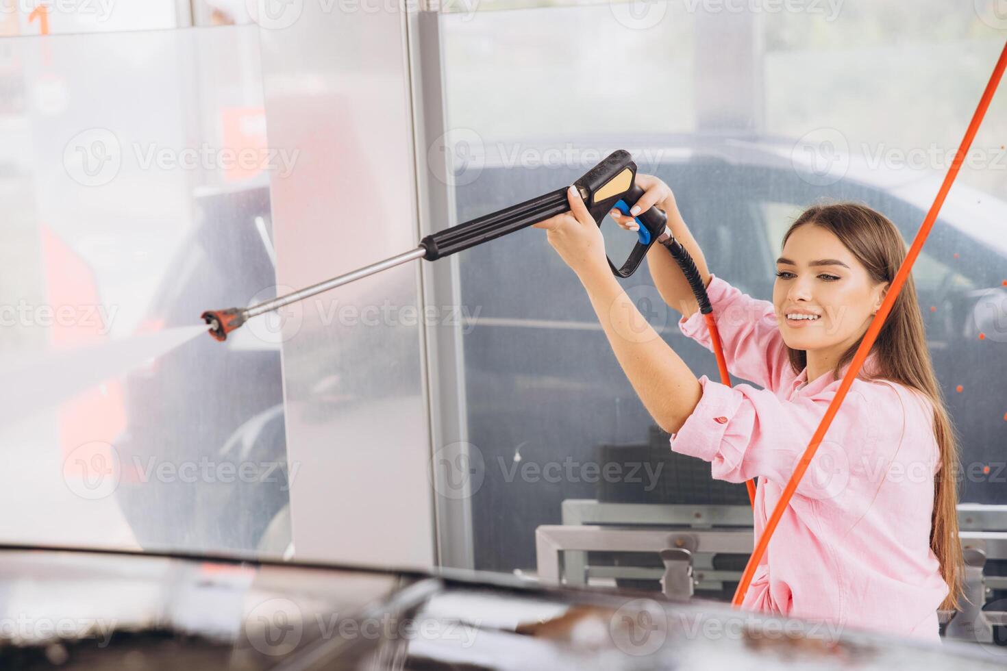Young Woman Enjoying a Car Wash with High-Pressure Hose photo