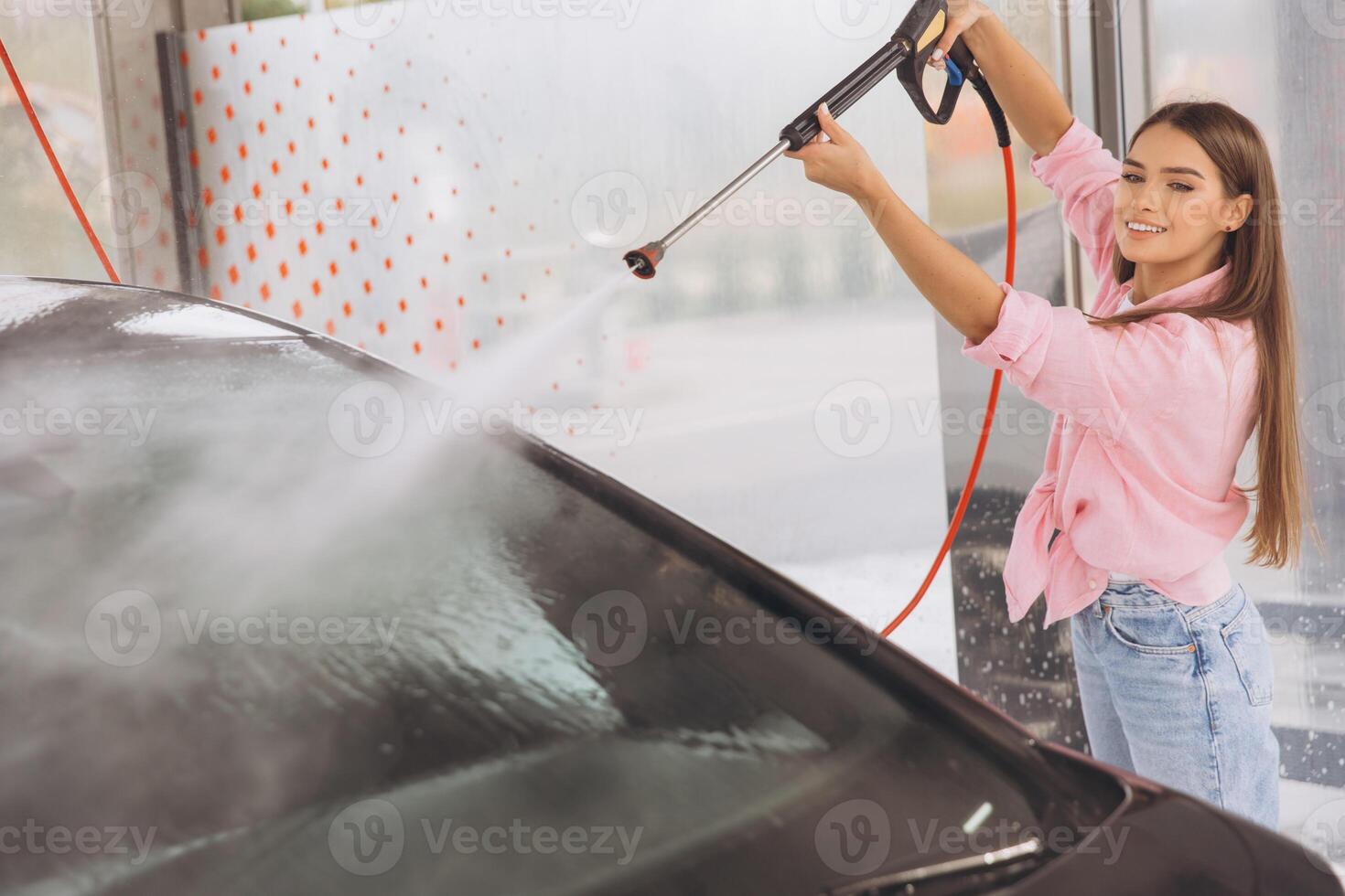 Smiling Woman Washing Car at a Self-Service Car Wash photo