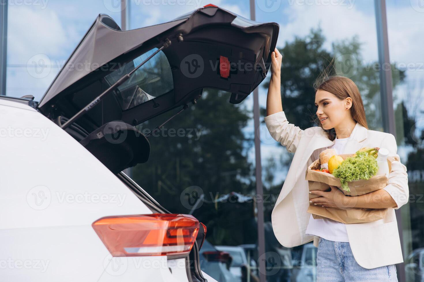 Woman Loading Groceries Into Car Trunk at Parking Lot photo