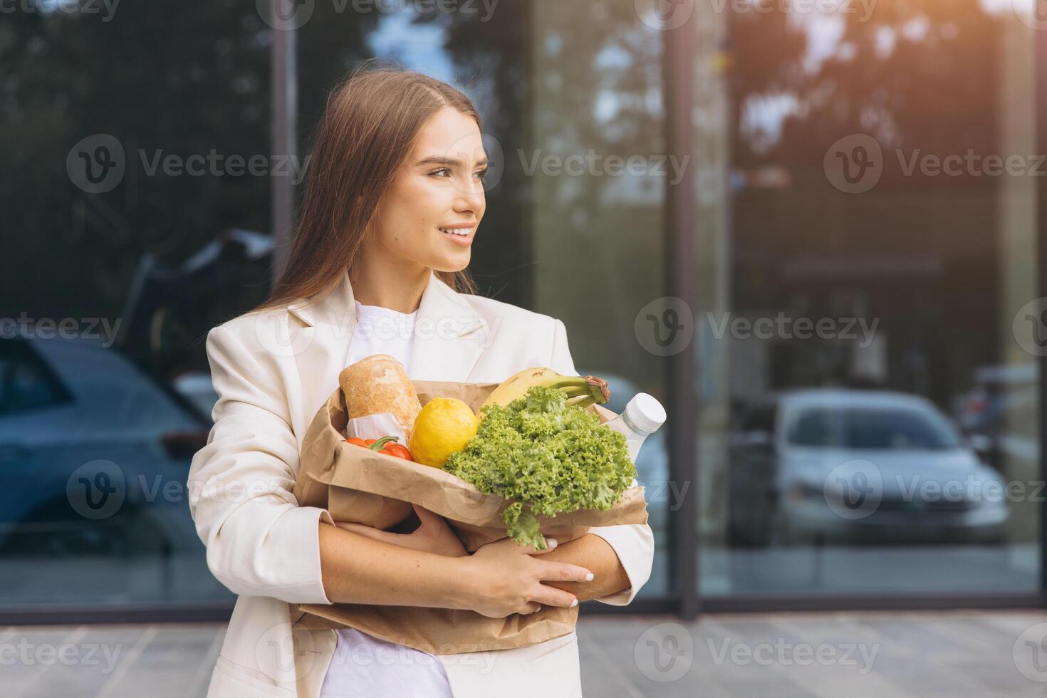 Young Woman Carrying Paper Bag Filled With Fresh Groceries Outdoors photo