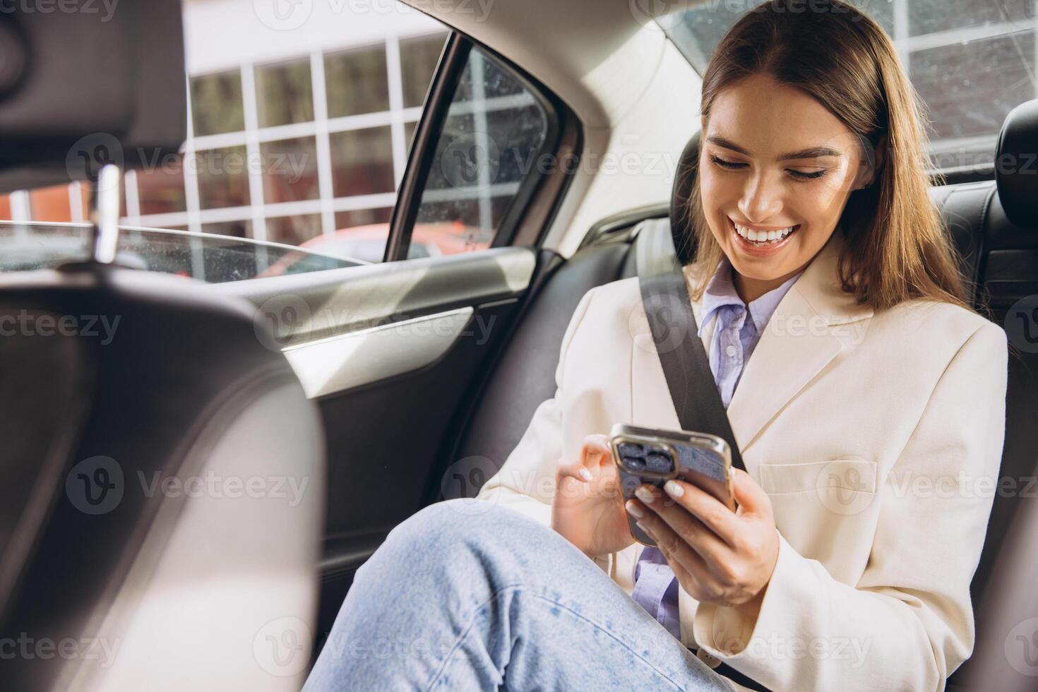 Smiling Woman Using Smartphone While Traveling in Car photo