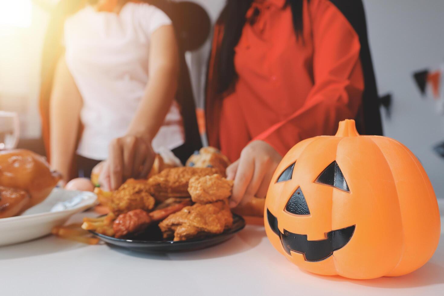friendship, holiday and people concept - group of happy smiling friends in halloween costumes of vampire, devil, witch and cheetah at home party photo
