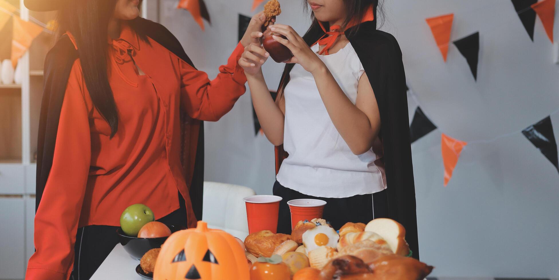 friendship, holiday and people concept - group of happy smiling friends in halloween costumes of vampire, devil, witch and cheetah at home party photo