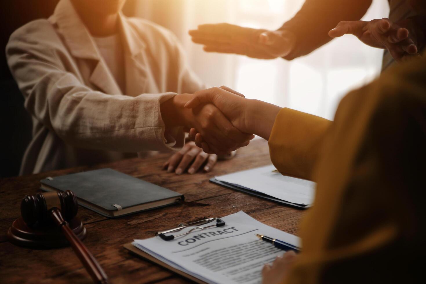 Lawyer shaking hands with a client making about documents, contracts, agreements, cooperation agreements with a female client at the lawyer's desk and a hammer at the table. photo