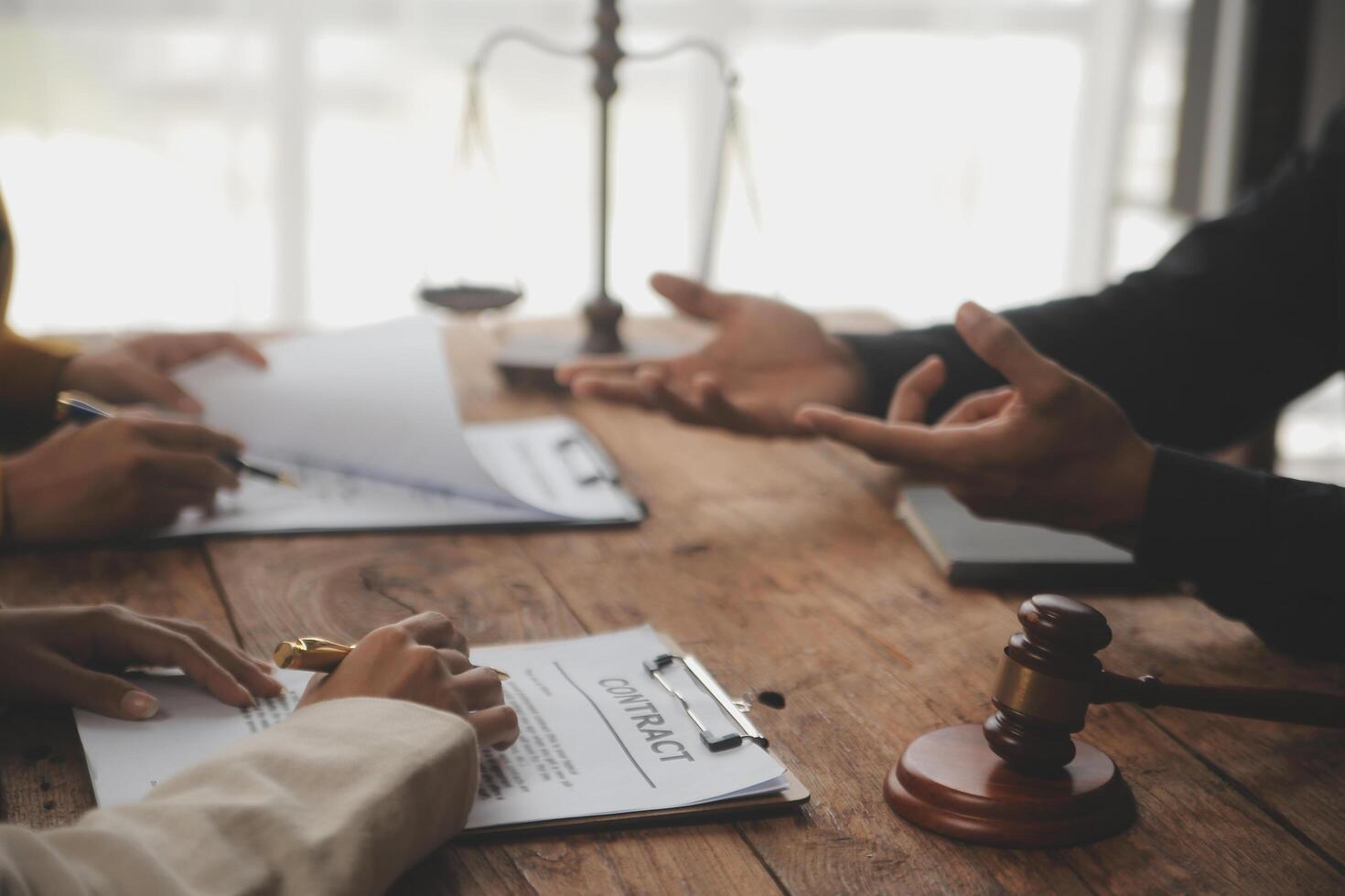 Business and lawyers discussing contract papers with brass scale on desk in office. Law, legal services, advice, justice and law concept picture with film grain effect photo