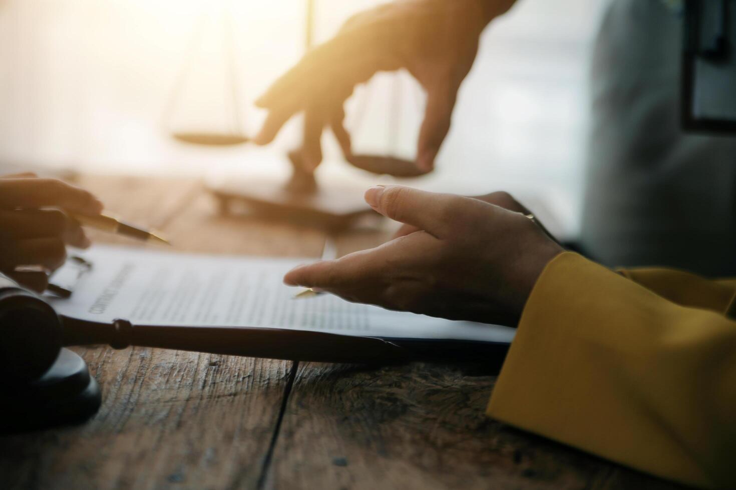 Business and lawyers discussing contract papers with brass scale on desk in office. Law, legal services, advice, justice and law concept picture with film grain effect photo