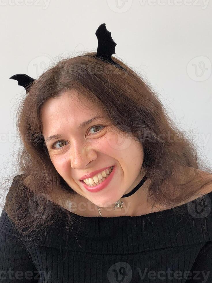 Smiling woman with Halloween bat wings on hair. Halloween, festivity and creativity concept photo
