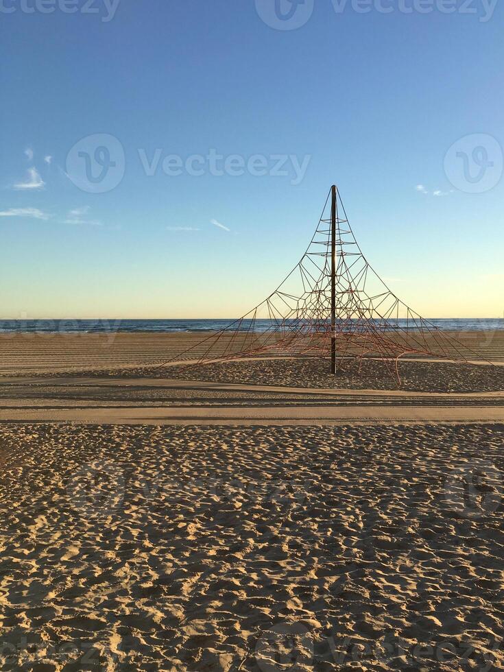 A tranquil beach landscape showcasing an intricate artistic sculpture with ropes set against a beautiful sunset backdrop photo